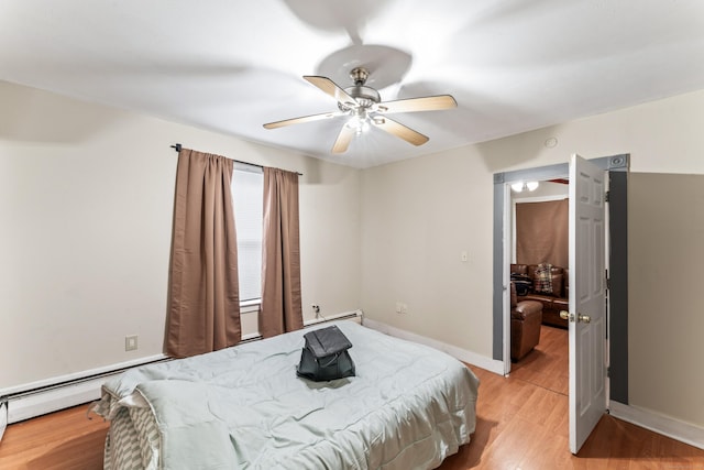 bedroom featuring ceiling fan, light hardwood / wood-style flooring, and a baseboard heating unit