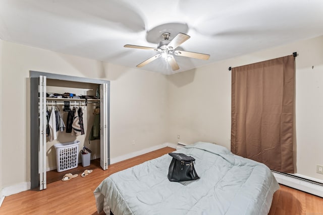 bedroom featuring ceiling fan, wood-type flooring, a closet, and a baseboard heating unit