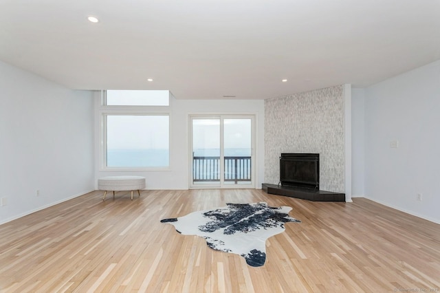 living room with a tiled fireplace and light hardwood / wood-style floors