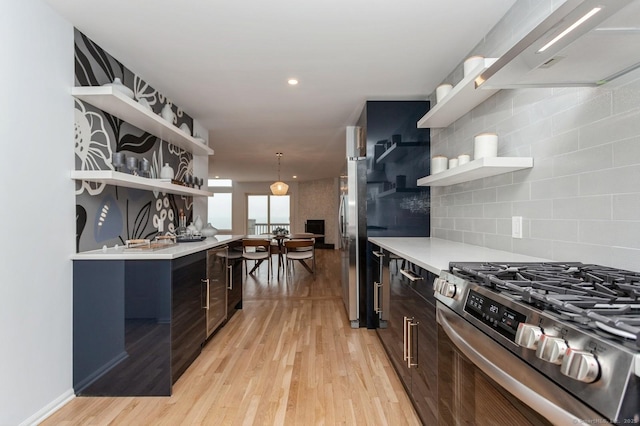 kitchen with dark brown cabinetry, tasteful backsplash, light wood-type flooring, and stainless steel gas stove