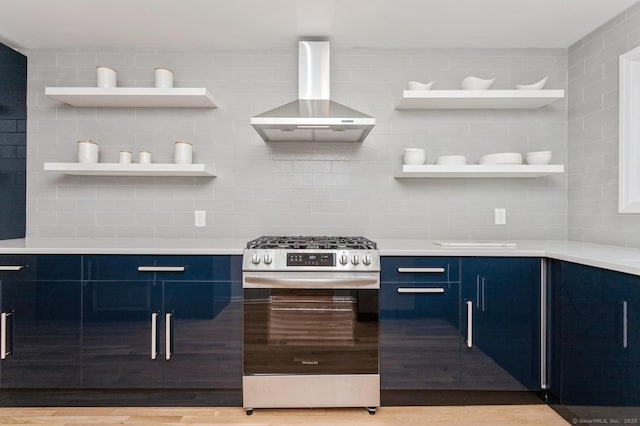 kitchen with tasteful backsplash, gas range, blue cabinetry, and wall chimney exhaust hood