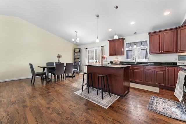 kitchen with pendant lighting, sink, vaulted ceiling, and a kitchen island