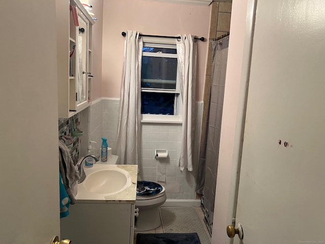 bathroom with vanity, toilet, a shower with shower curtain, and tile walls