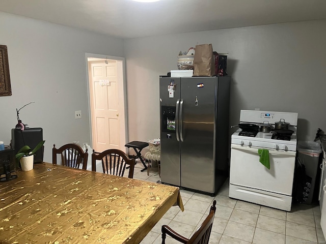 kitchen with light tile patterned flooring, white gas stove, and stainless steel refrigerator with ice dispenser