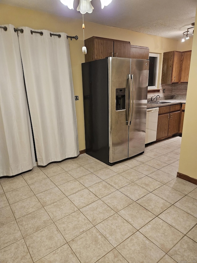 kitchen with light tile patterned flooring, a textured ceiling, white dishwasher, and stainless steel fridge with ice dispenser