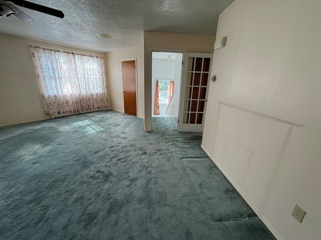 unfurnished room with ceiling fan, a textured ceiling, and carpet flooring