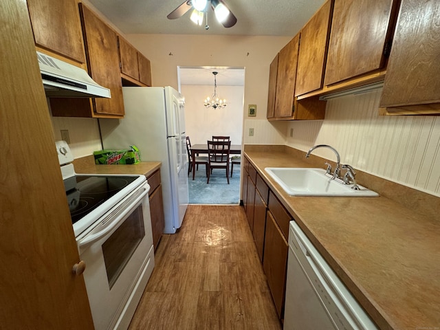 kitchen with pendant lighting, sink, white appliances, light hardwood / wood-style flooring, and ceiling fan with notable chandelier