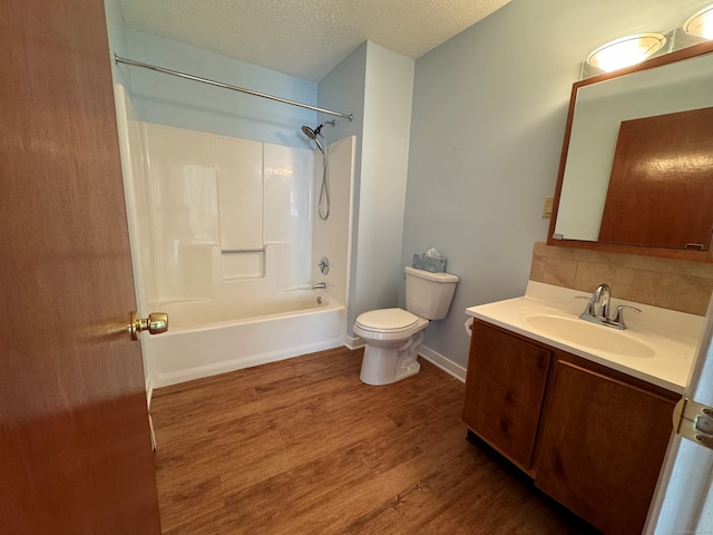 full bathroom featuring hardwood / wood-style flooring, vanity, a textured ceiling, bathtub / shower combination, and toilet