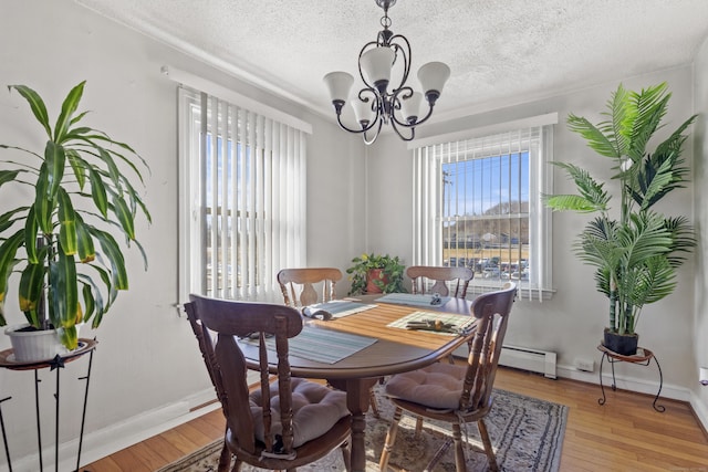 dining area with a healthy amount of sunlight, a textured ceiling, wood-type flooring, and a notable chandelier