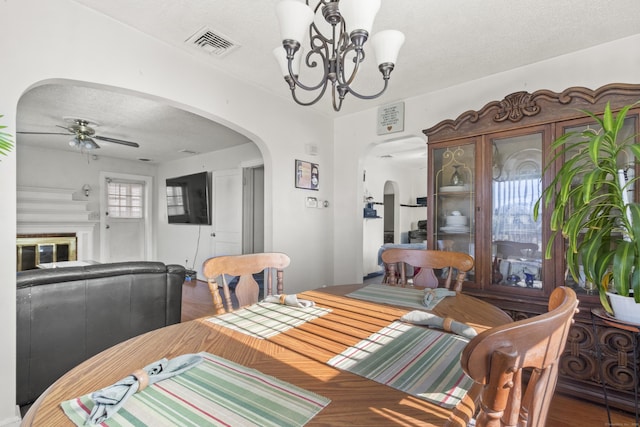 dining space featuring hardwood / wood-style flooring, ceiling fan with notable chandelier, and a textured ceiling