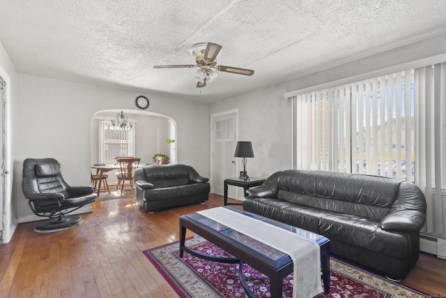 living room featuring hardwood / wood-style floors, ceiling fan with notable chandelier, and a textured ceiling