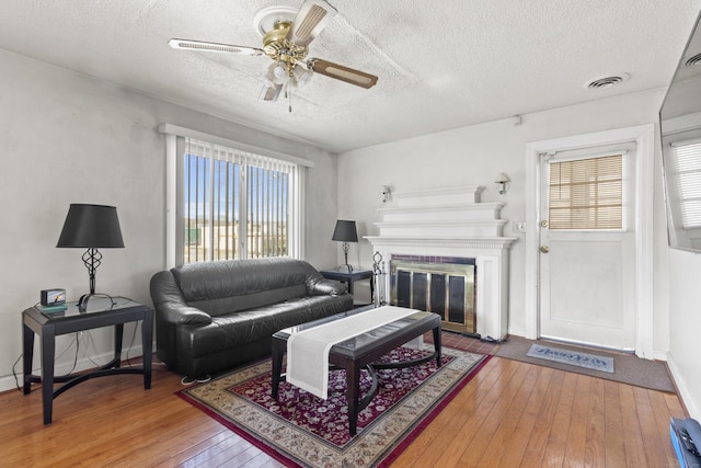 living room with ceiling fan, hardwood / wood-style floors, and a textured ceiling