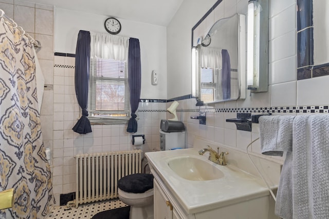 bathroom with tile walls, vanity, radiator heating unit, and toilet