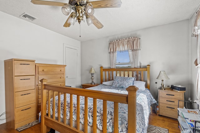 bedroom featuring ceiling fan, wood-type flooring, and a textured ceiling