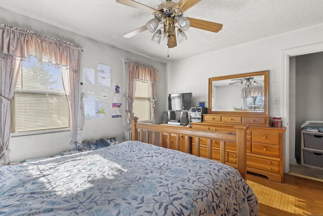 bedroom with hardwood / wood-style flooring, ceiling fan, and a textured ceiling