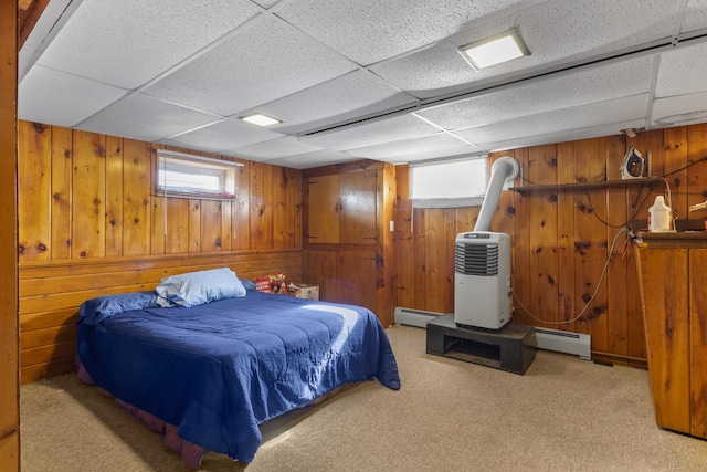 carpeted bedroom featuring a baseboard radiator, a paneled ceiling, and wood walls