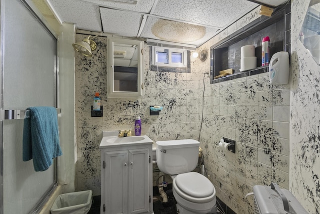 bathroom featuring vanity, a shower with shower door, a drop ceiling, and toilet