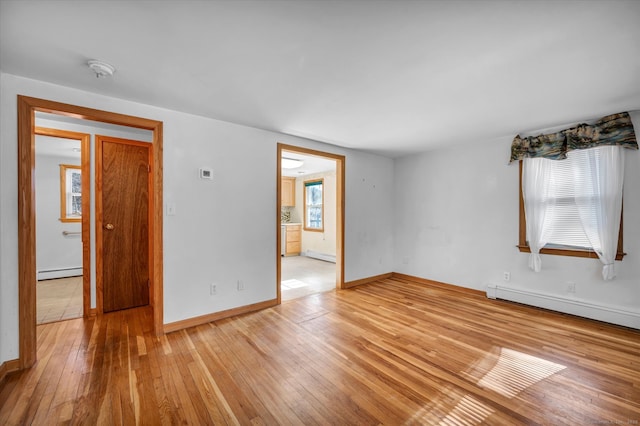 empty room featuring a baseboard radiator and light hardwood / wood-style floors