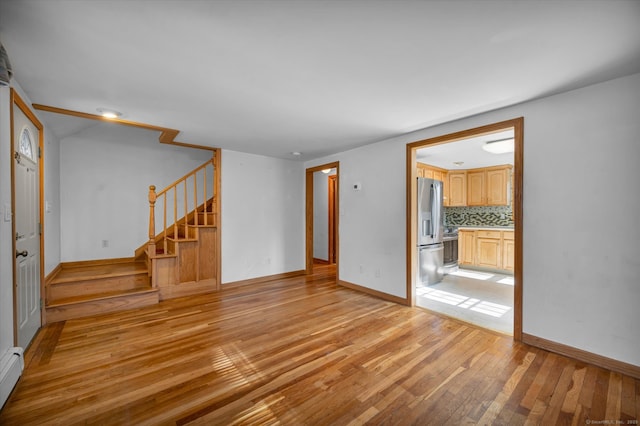 unfurnished living room featuring a baseboard radiator and light hardwood / wood-style floors