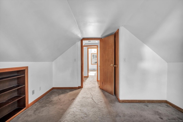 bonus room with vaulted ceiling and light carpet