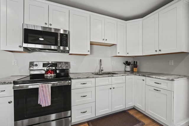 kitchen featuring appliances with stainless steel finishes, sink, white cabinets, and light stone counters