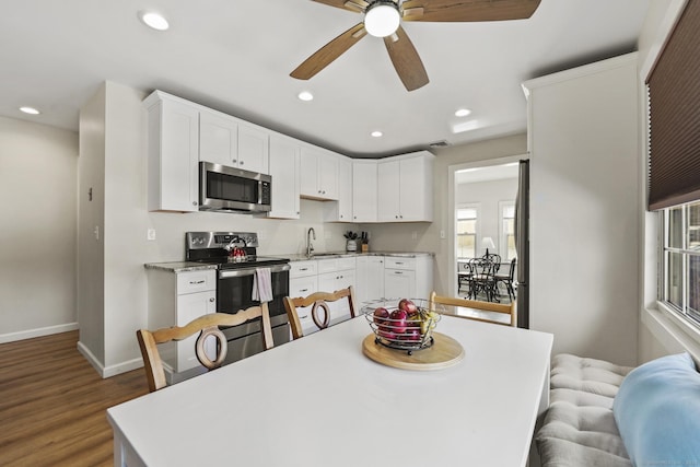 kitchen featuring appliances with stainless steel finishes, sink, wood-type flooring, and white cabinets