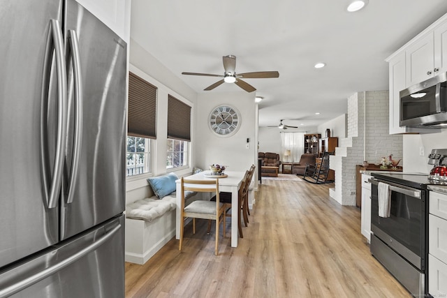 kitchen with stainless steel appliances, white cabinetry, ceiling fan, and light hardwood / wood-style floors