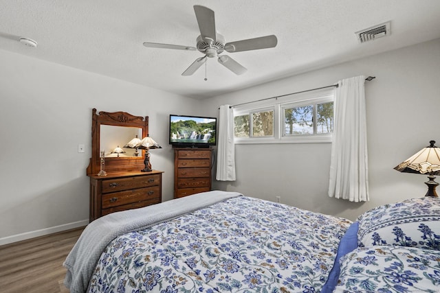 bedroom with ceiling fan, hardwood / wood-style floors, and a textured ceiling