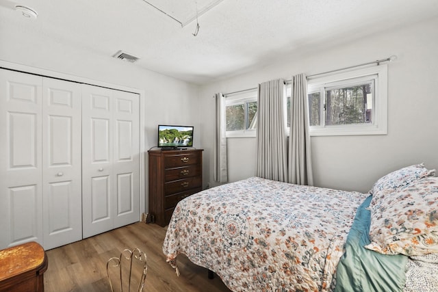 bedroom with light hardwood / wood-style floors, a closet, and a textured ceiling