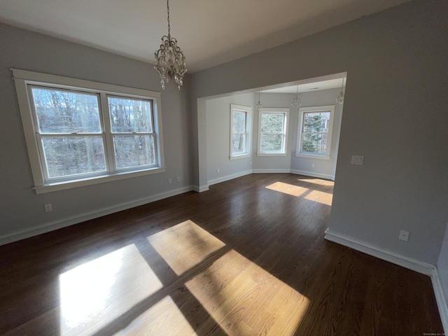 empty room featuring dark wood-type flooring and a chandelier