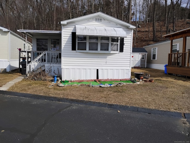 manufactured / mobile home featuring a storage unit, an outbuilding, and a porch