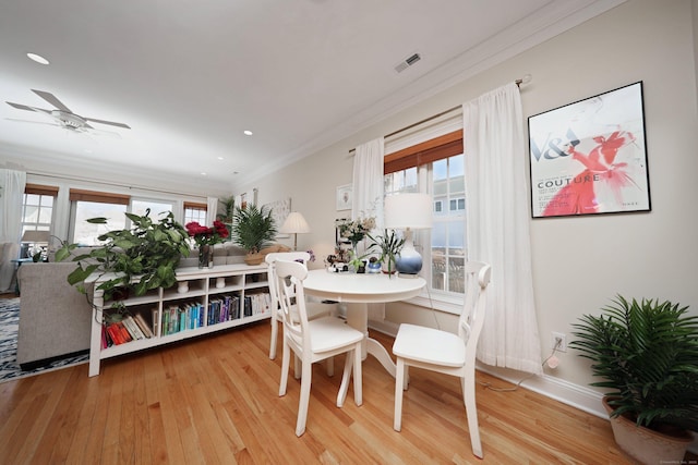 dining space with crown molding, light hardwood / wood-style flooring, and ceiling fan