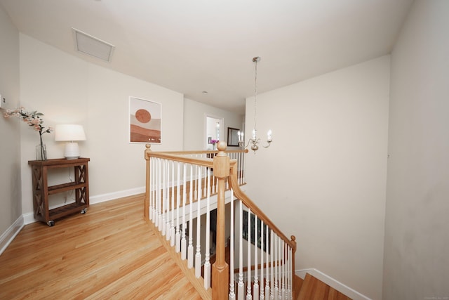 staircase with hardwood / wood-style floors and a notable chandelier