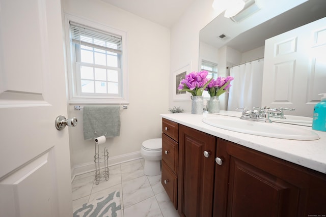 bathroom featuring plenty of natural light, toilet, and vanity