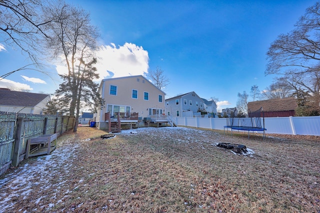 rear view of house with a trampoline and a wooden deck