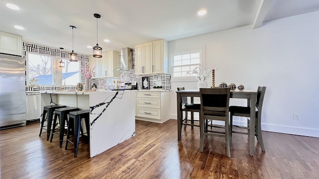 kitchen featuring hanging light fixtures, dark hardwood / wood-style flooring, stainless steel appliances, cream cabinets, and decorative backsplash