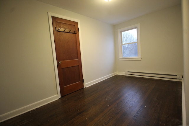 spare room with baseboard heating and dark hardwood / wood-style flooring