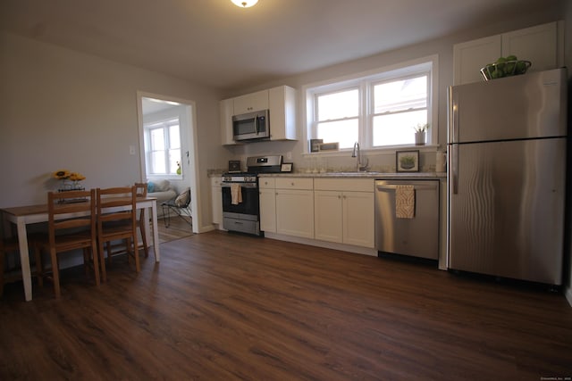 kitchen with sink, dark wood-type flooring, white cabinetry, stainless steel appliances, and light stone counters