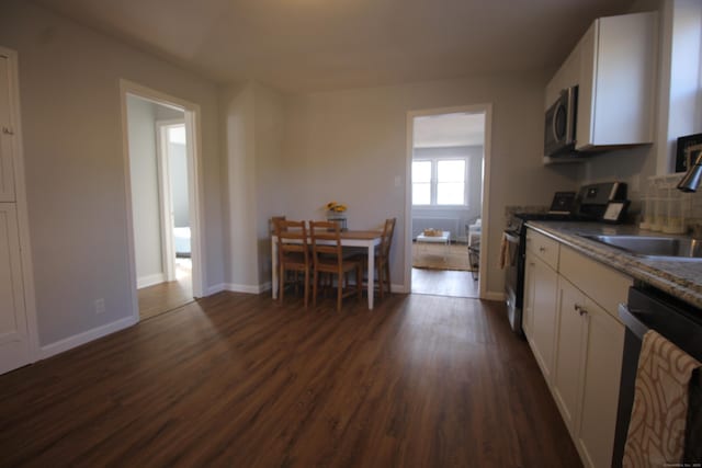 kitchen featuring white cabinetry, sink, dark stone countertops, stainless steel appliances, and dark wood-type flooring