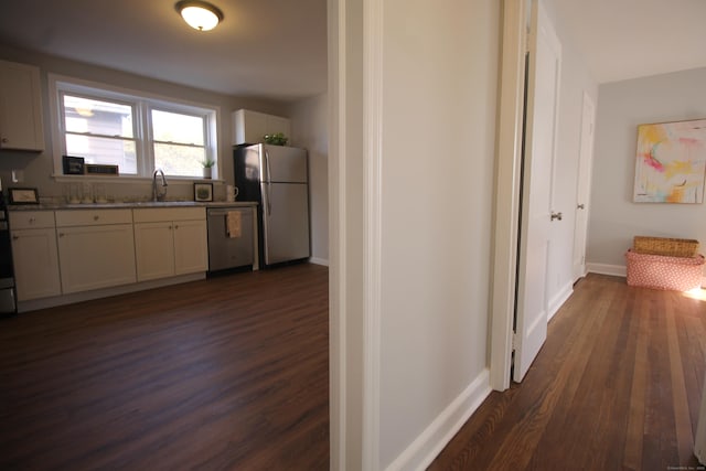 kitchen featuring sink, white cabinetry, appliances with stainless steel finishes, dark hardwood / wood-style floors, and light stone countertops