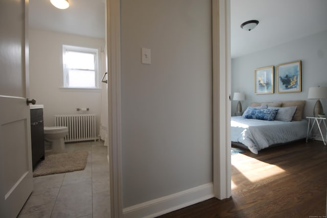 bedroom with radiator and hardwood / wood-style floors