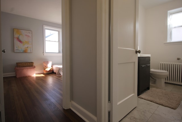 hallway featuring plenty of natural light, radiator heating unit, and light wood-type flooring