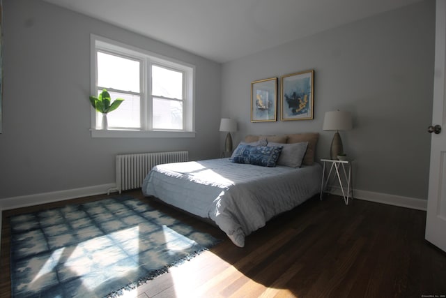 bedroom with dark hardwood / wood-style flooring and radiator