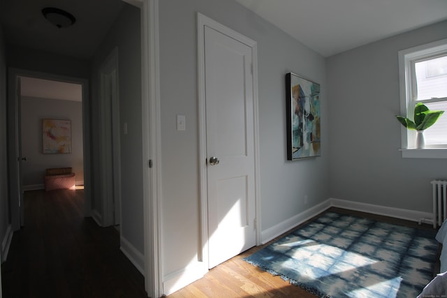 hallway featuring dark wood-type flooring and radiator heating unit