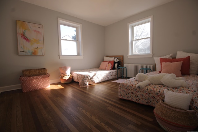 bedroom with dark hardwood / wood-style flooring and radiator