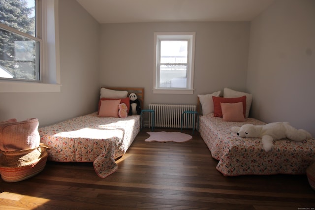 bedroom with dark hardwood / wood-style floors and radiator