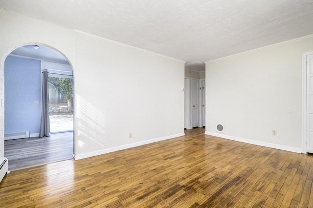 unfurnished room featuring crown molding, wood-type flooring, and baseboard heating