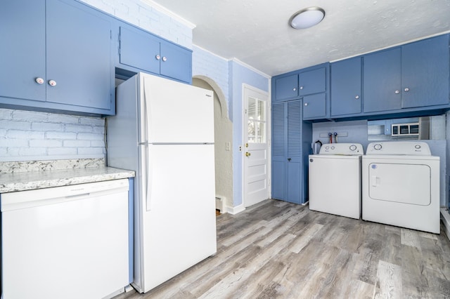 kitchen with blue cabinets, light wood-type flooring, white appliances, a textured ceiling, and washer and clothes dryer