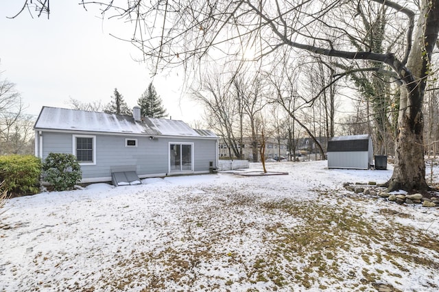 snow covered back of property with a storage shed