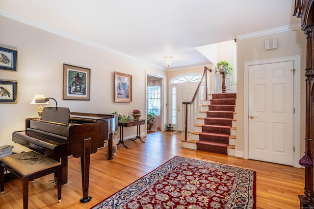 foyer entrance with crown molding and light hardwood / wood-style floors